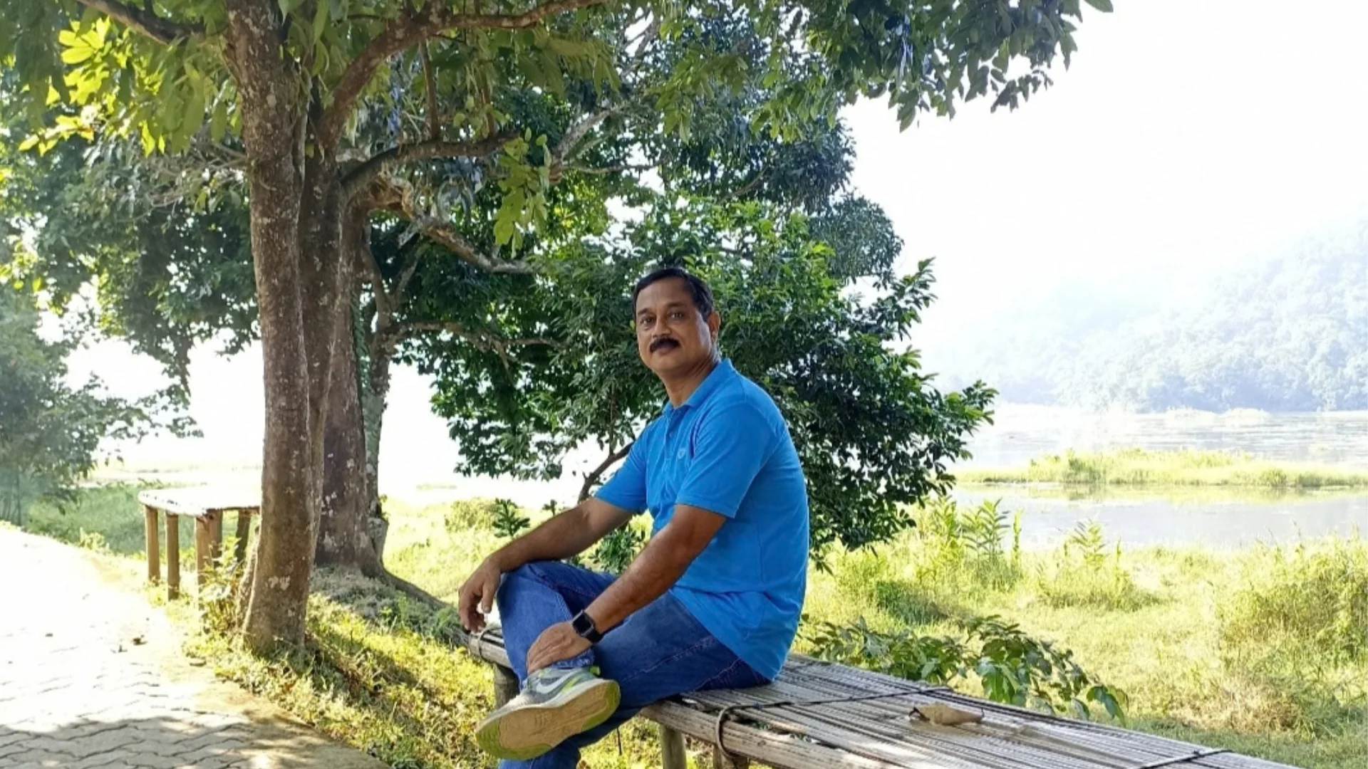 Amitabh Sarma, founder of Tiger Camp Kaziranga, sitting beside the natural landscape of Kaziranga, Assam